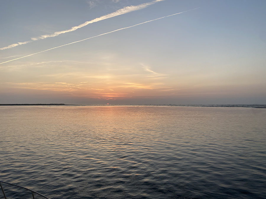 Sunset over calm ocean waters during a burial at sea service
